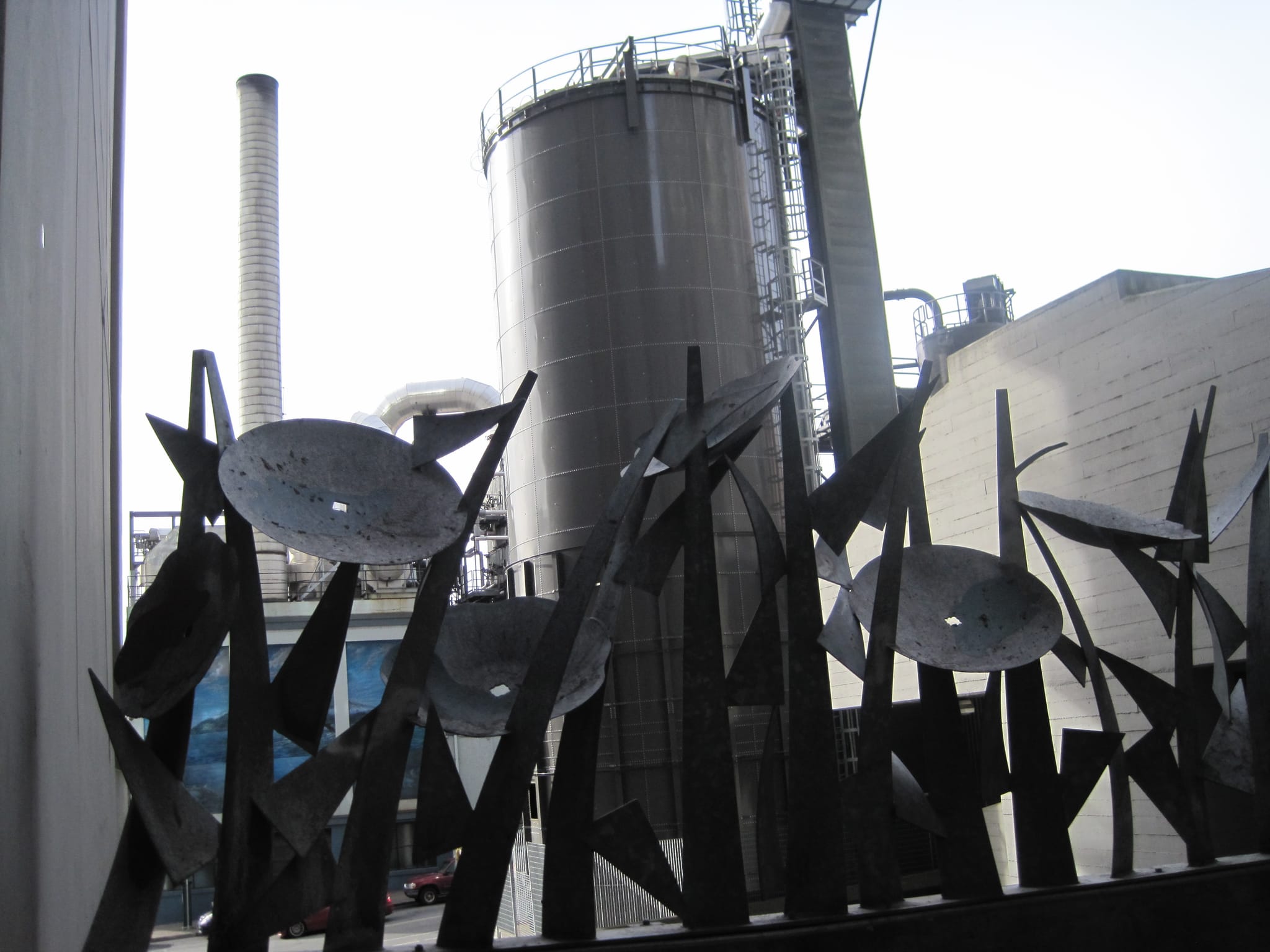 Metal flowers in front of some industrial stuff.